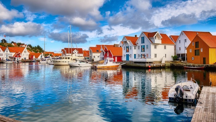 Boats docked in a Norwegian harbor with colorful houses
