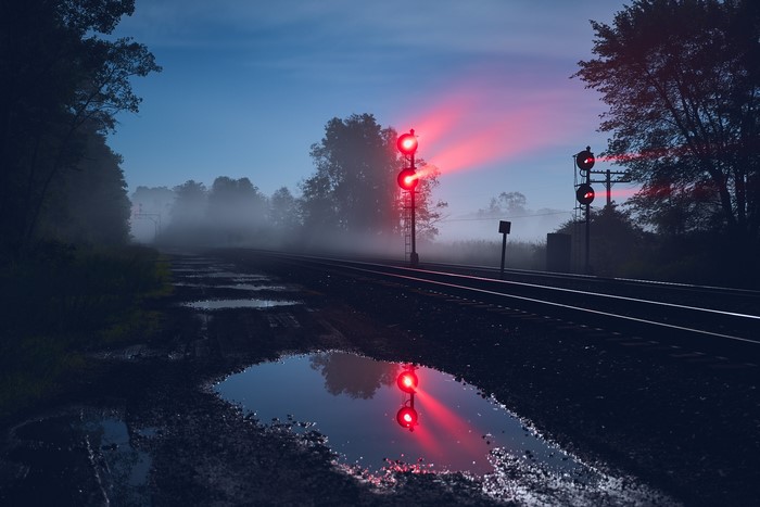 Train signals at night with fog and puddles