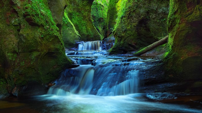 Moss-covered gorge with cascading waterfalls in Scotland