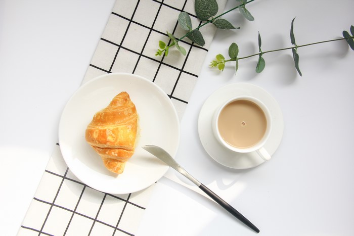 Croissant and coffee with eucalyptus leaves