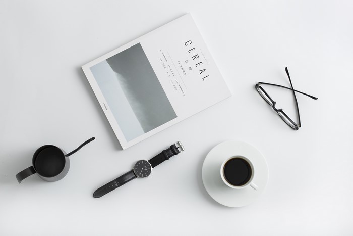 Cereal magazine, coffee cup, glasses, and watch