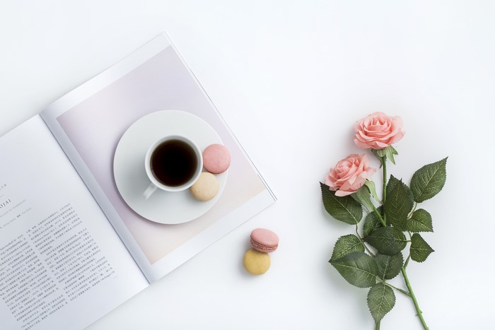 Coffee cup and macarons on a magazine with roses