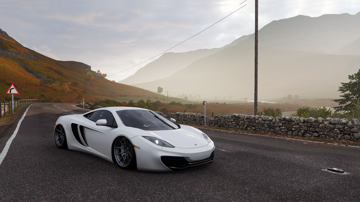 White McLaren 12C driving on a winding road