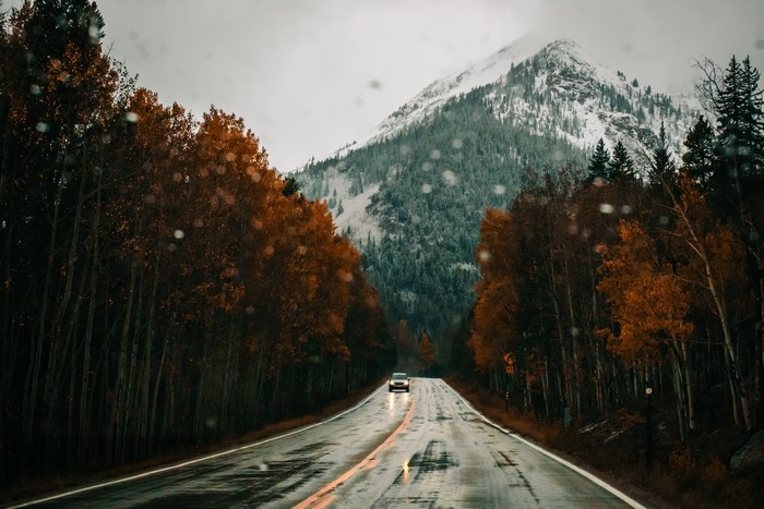 Car driving on a wet mountain road in fall