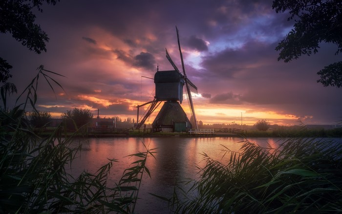 Windmill at sunset over water in the Netherlands