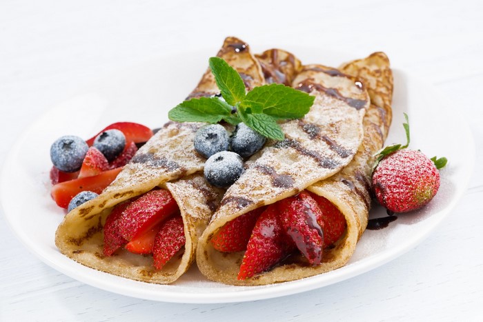 Crepes with strawberries, blueberries, and powdered sugar