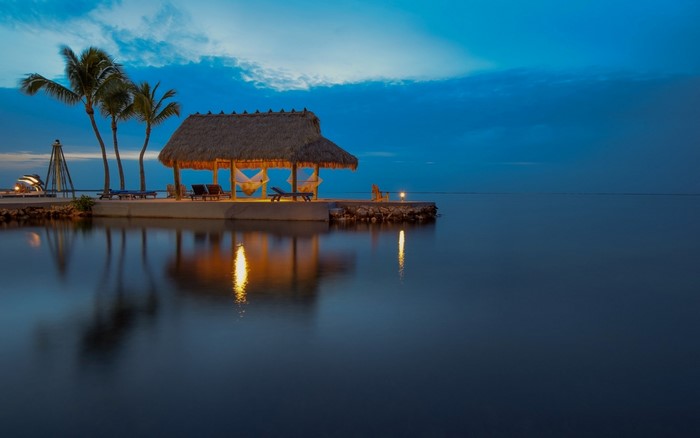 Tropical hut with hammocks on a pier at dusk