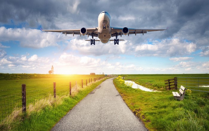 Airplane flying over a rural landscape with a road