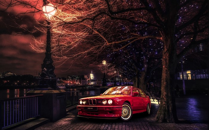 Red BMW E30 parked by a lamppost in London at night