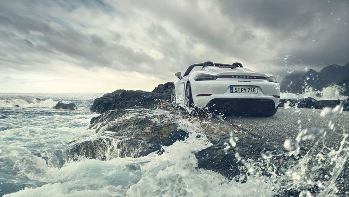White Porsche 718 Spyder on rocky seashore with waves