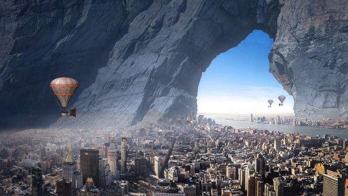 Hot air balloons over New York City through a rock arch