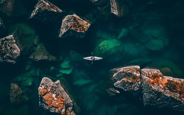 Kayaker in a rocky cove from above