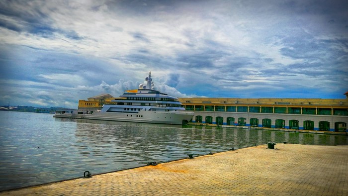 Large yacht docked at a pier with a building in the background