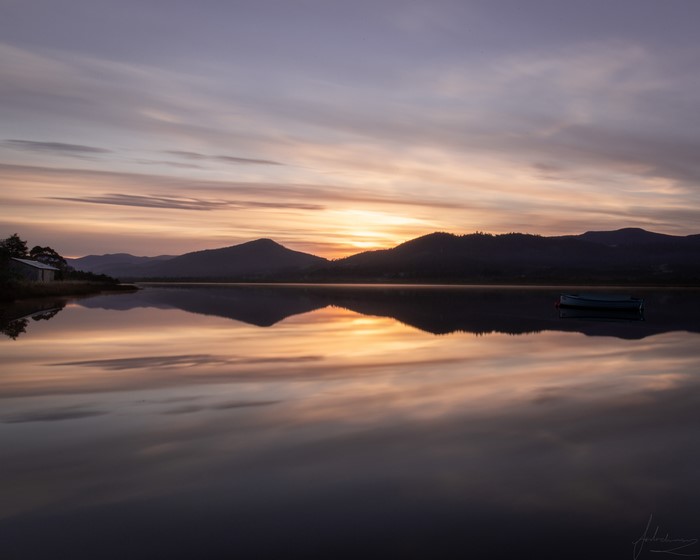 Tasmanian sunset over a lake with a boat