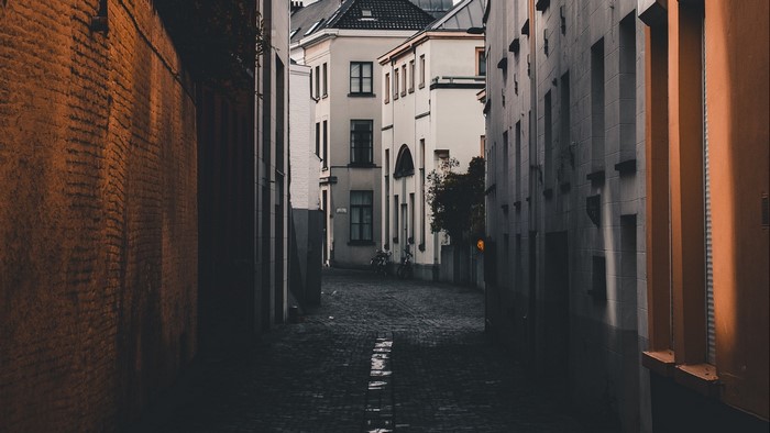 Narrow European alleyway with old buildings and cobblestone street