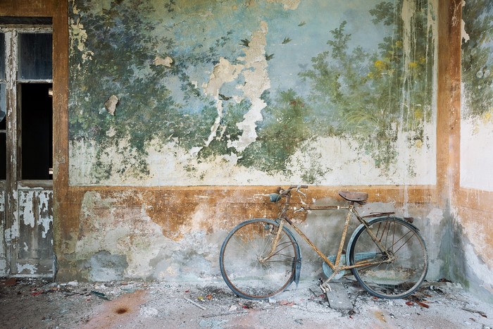 Rusty bicycle in a ruined room with a mural