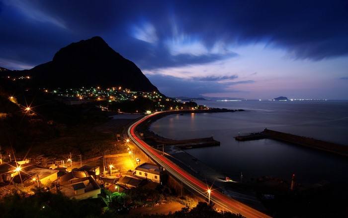 Coastal town at night with mountain and sea