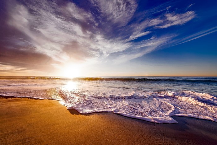Sunset over the ocean with waves on the beach