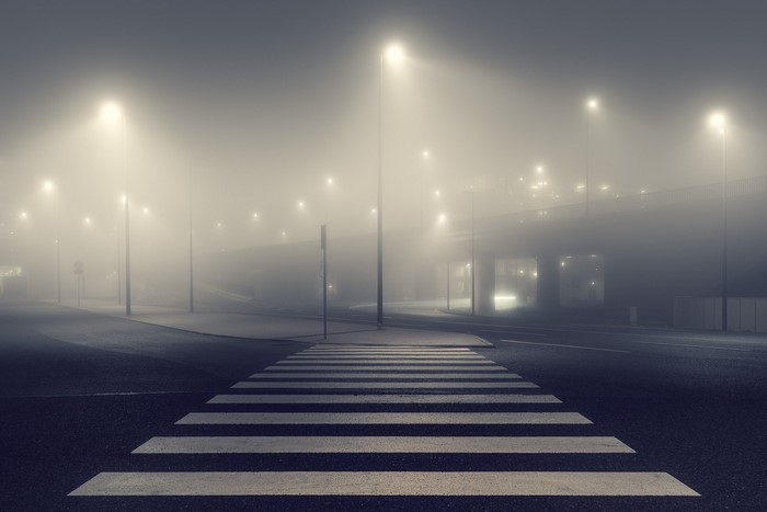 Crosswalk on a foggy street at night with streetlights