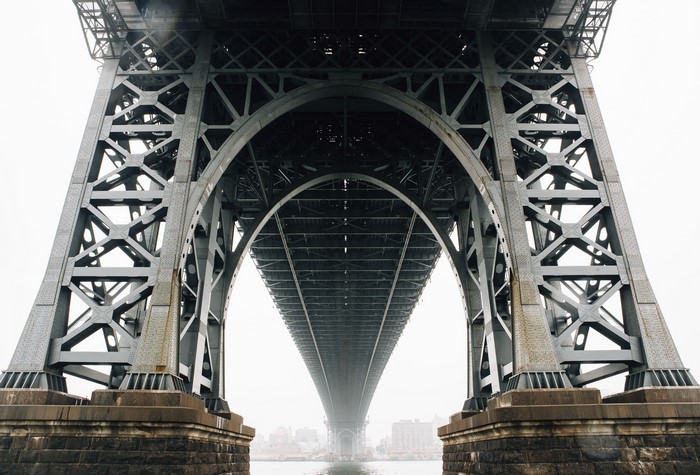 Underneath a large metal bridge with stone supports