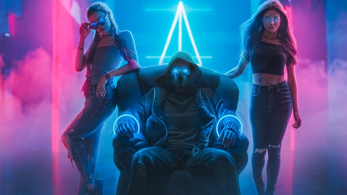 Faceless man in chair with women in neon nightclub