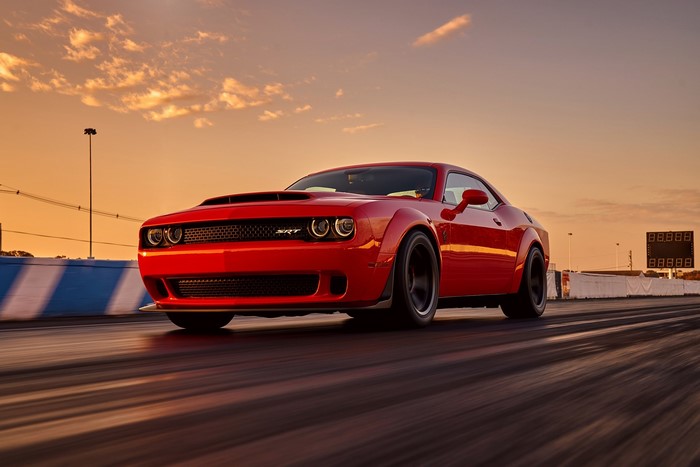 Red Dodge Challenger SRT Hellcat on a race track at sunset