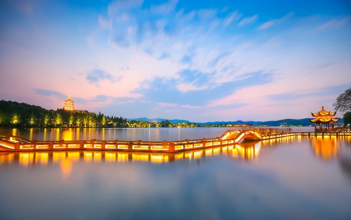 West Lake at dusk with illuminated bridge and pagoda