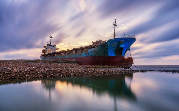 Abandoned ship on a rocky shore at sunset