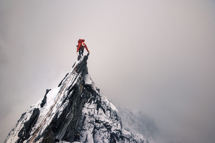 Climber on a snowy mountain peak in mist