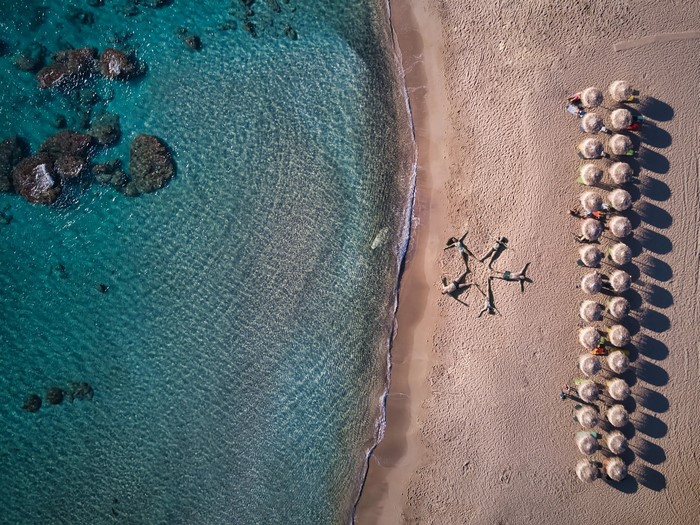 Aerial view of people sunbathing on a sandy beach next to the ocean