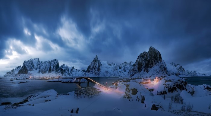 Snowy mountains and village with bridge at dusk