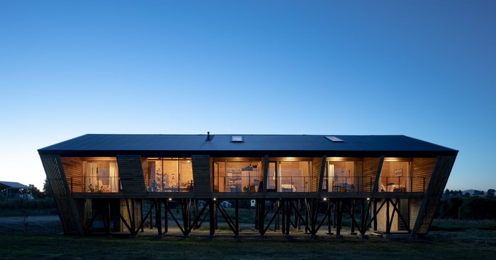 Modern wooden cabin on stilts at dusk