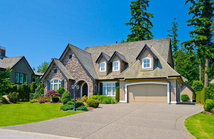 Luxury stone and stucco house with garage and manicured lawn