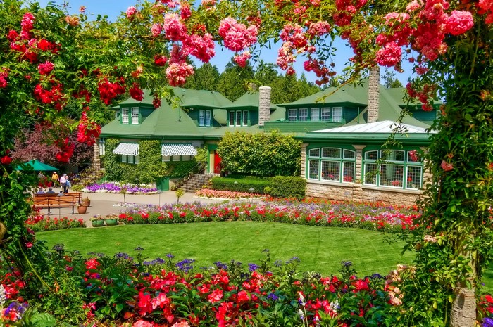 A grand mansion with a vibrant floral garden