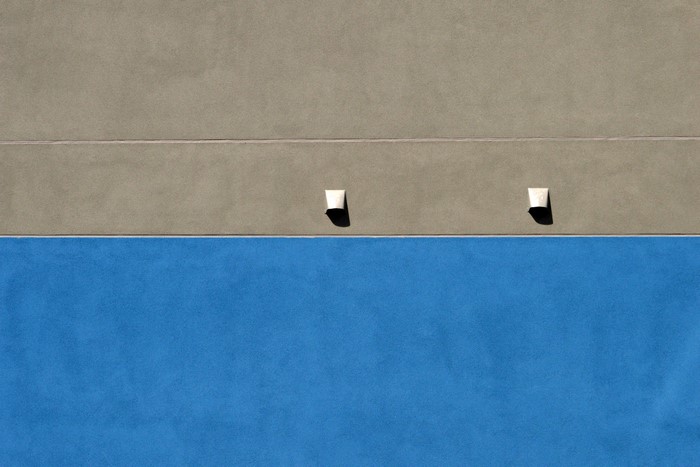 Two lights on a building wall with blue and tan sections