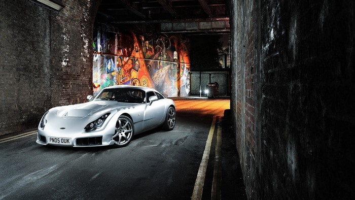 Silver TVR Sagaris sports car parked in alley with graffiti