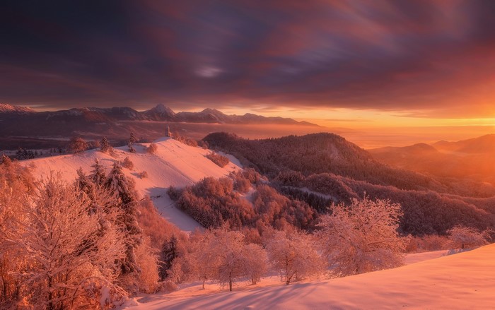 Snowy mountain landscape at sunset with a church on a hill