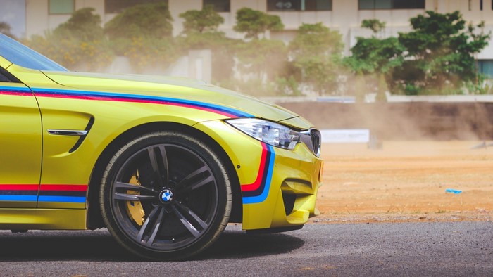 Yellow BMW M4 with racing stripes
