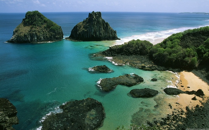 Two rocky islands in a turquoise ocean with a sandy beach