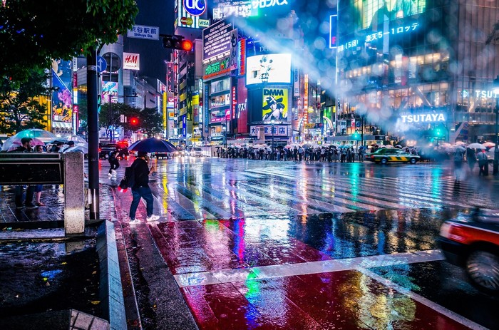 Shibuya Crossing at night with neon lights and rain