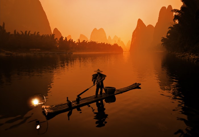 Fisherman on a raft at dusk
