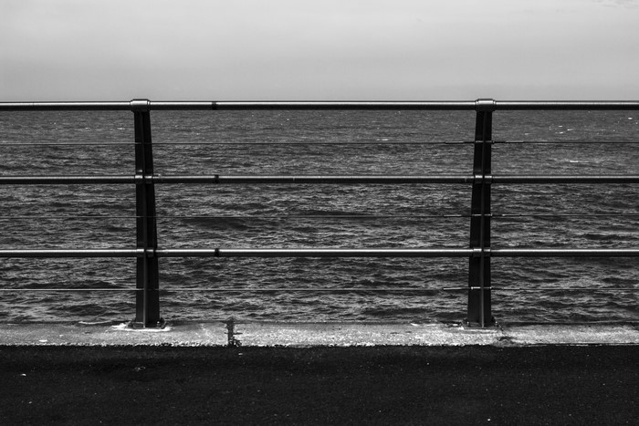 Monochrome photography of a railing by the sea