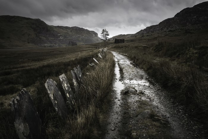 Dirt road with stone wall and abandoned building