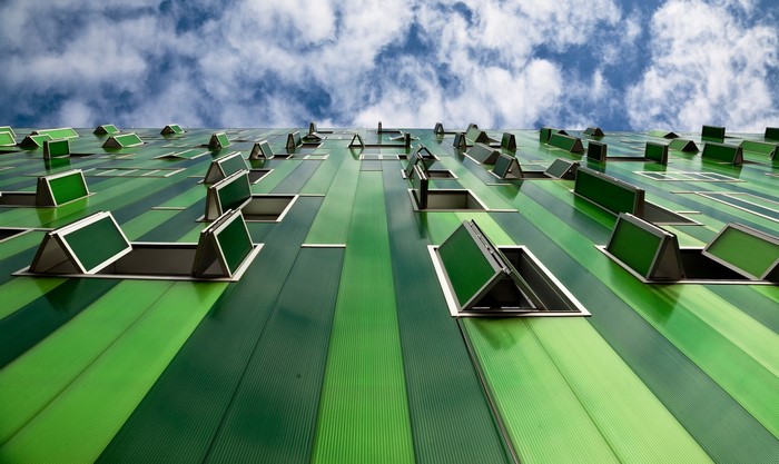 Green building facade with open windows against blue sky