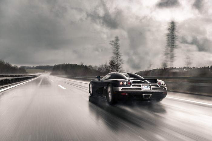 Black Koenigsegg driving on a wet road