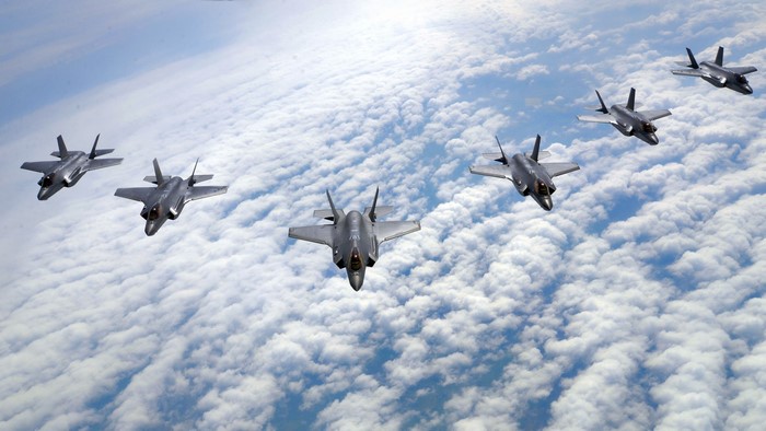 Formation of F-35A Lightning II military aircraft flying above clouds
