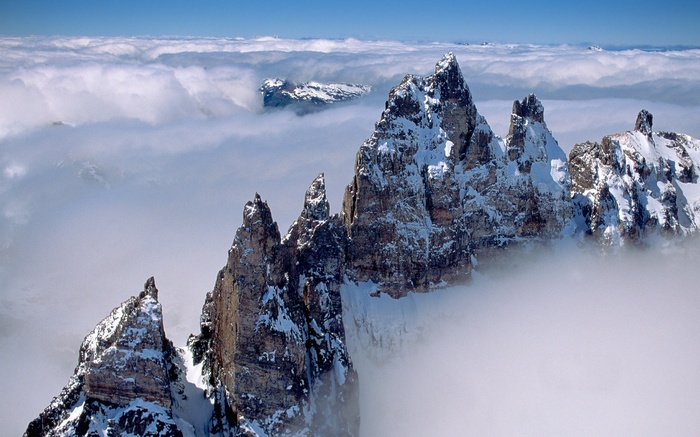 Snow-covered jagged mountain peaks above clouds