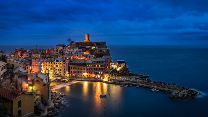 Vernazza, Italy at dusk with illuminated buildings and harbor