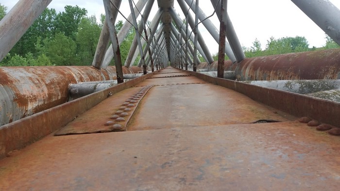 Old rusty metal bridge structure with pipes