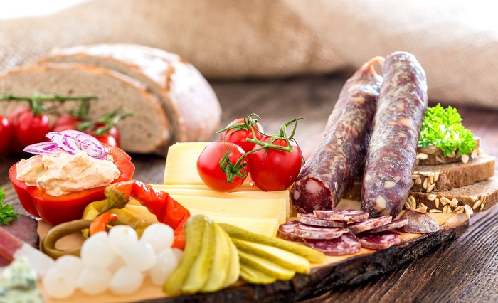 Charcuterie board with sausage, cheese, bread, and vegetables